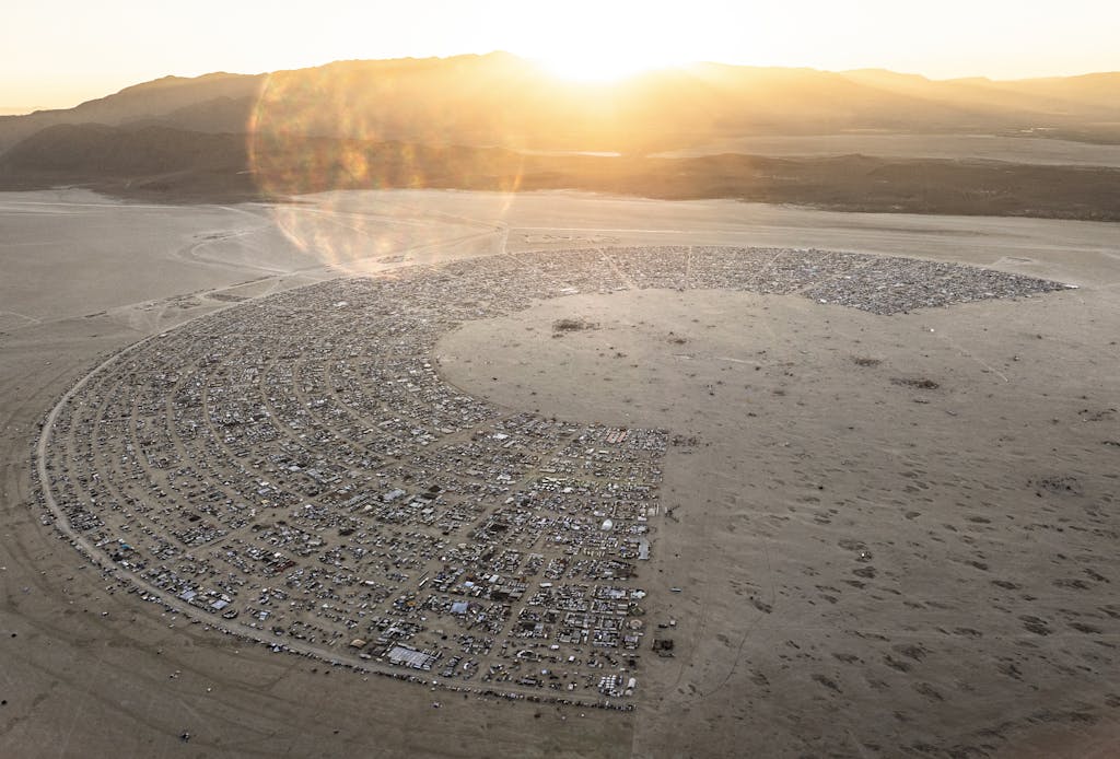 Aerial photography of Burning Man festival with sunrise over Black Rock City.