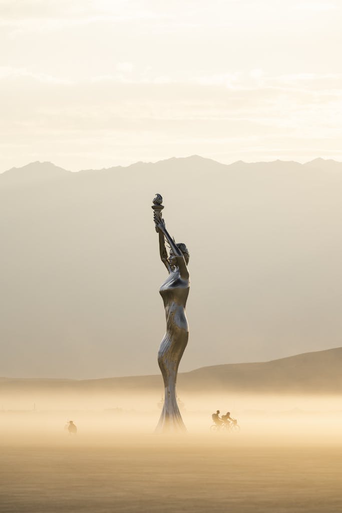 Ethereal sculpture in misty desert at sunrise, capturing serene beauty.