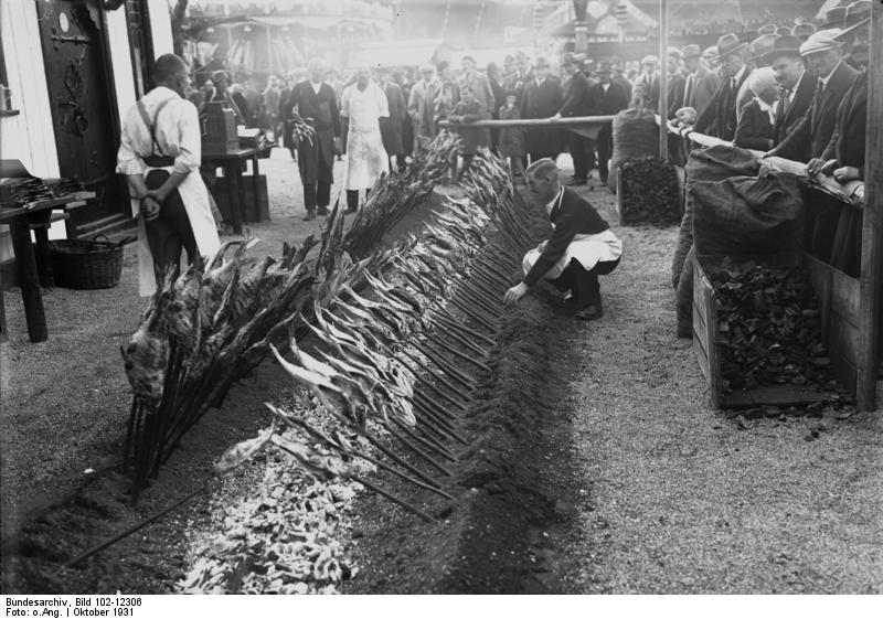 The Munich Oktoberfest 1931 with Steckerlfisch roasted fish on glowing coals, which are sold directly from the spit, a delicacy on the festival meadow.