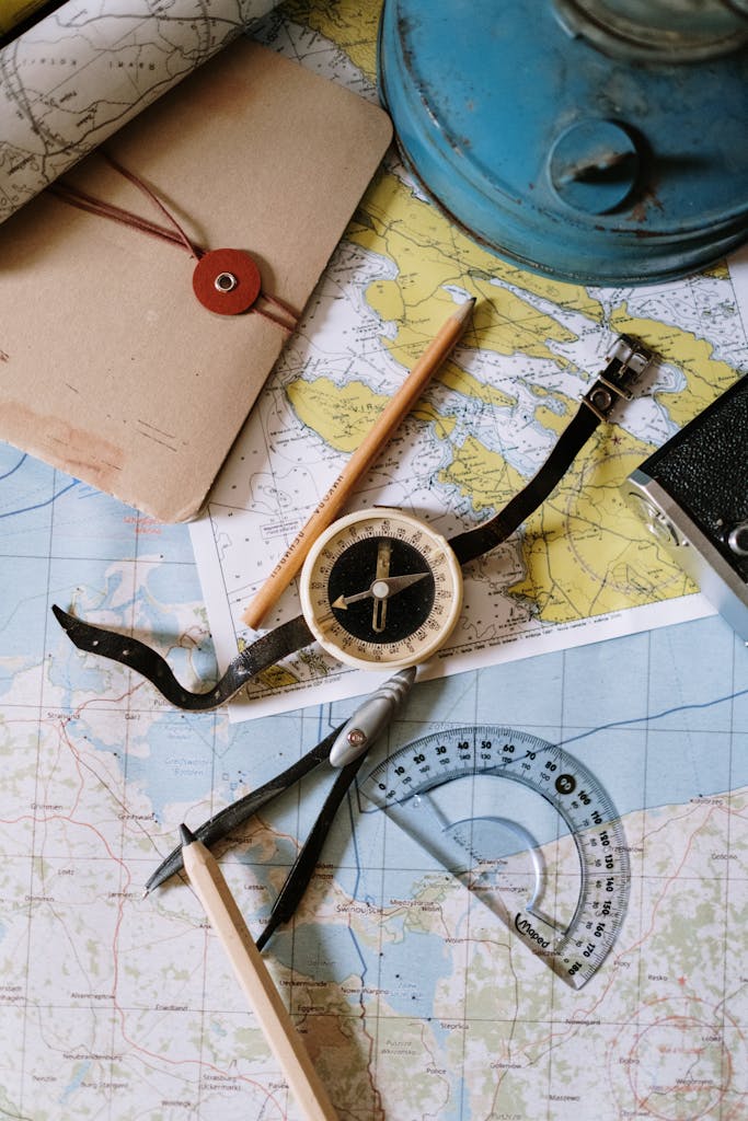 Flat lay of vintage compass, protractor, and maps for navigation study.