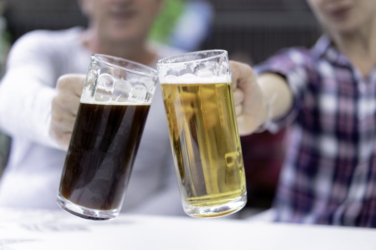 Two men toast with light and dark beer steins at Oktoberfest.