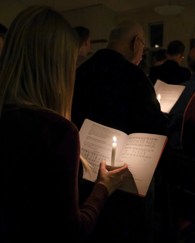 A serene candlelit church service with hymn books during Christmas Eve.