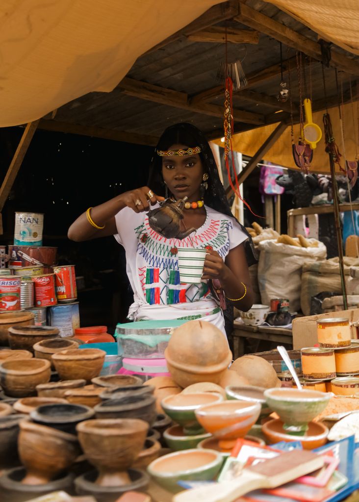 A vibrant scene at an African market featuring a woman artist crafting traditional pottery.