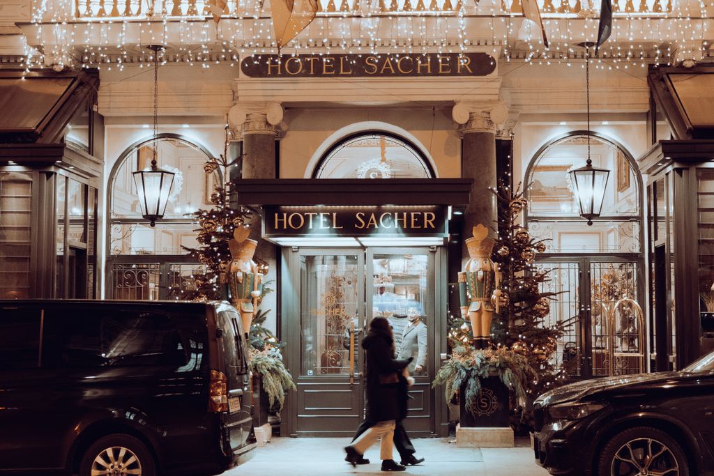 Front view of Hotel Sacher in Vienna, Austria adorned with festive Christmas lights and decorations.