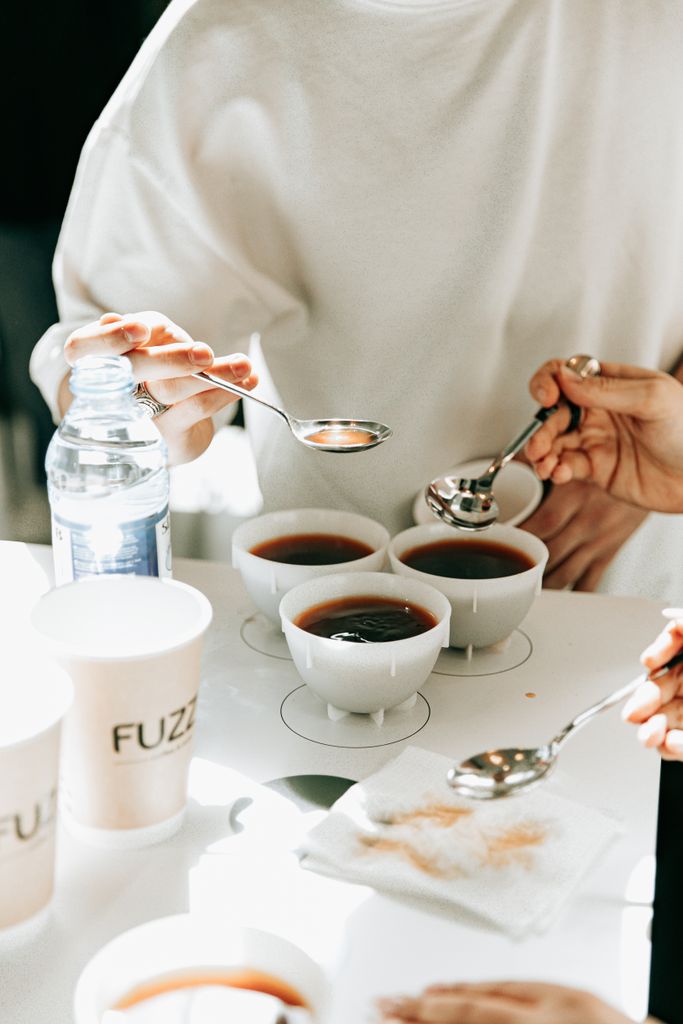 Hands holding spoons in a tea tasting session in Baku, Azerbaijan.
