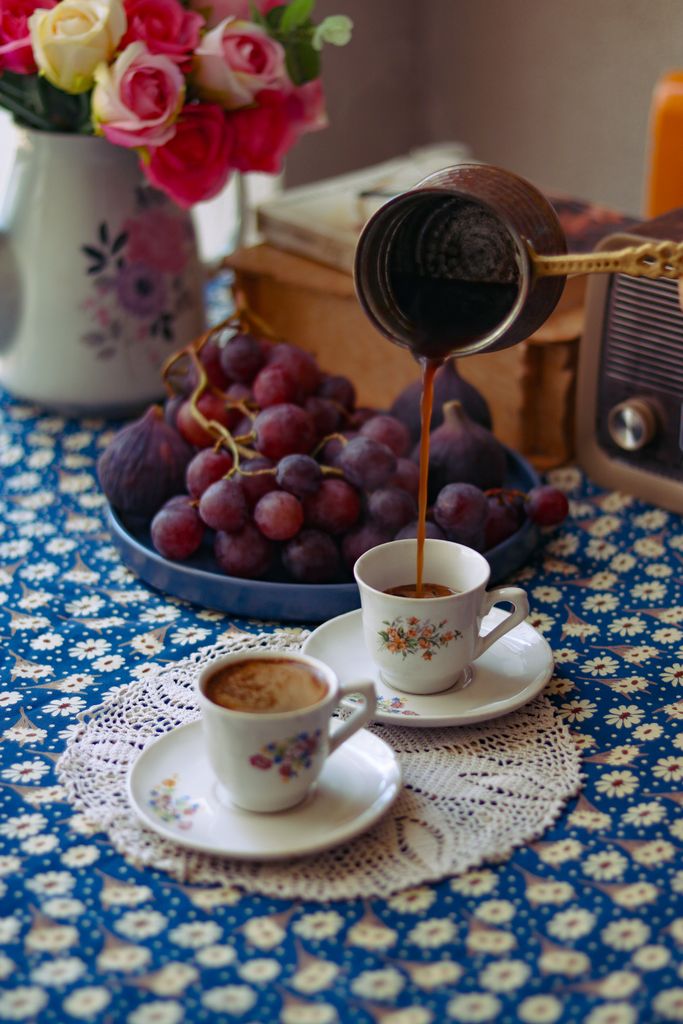 Rustic vintage coffee scene with pouring cezve, fresh grapes, and floral decor.